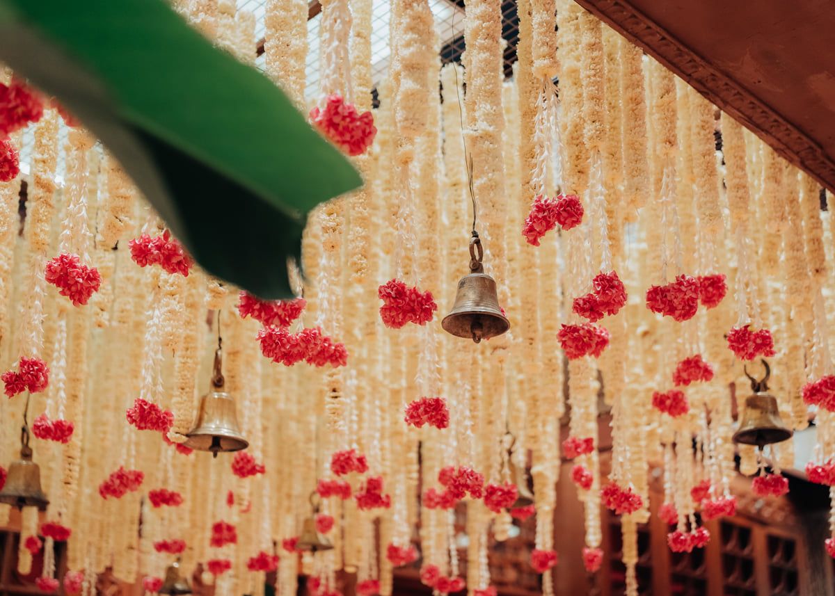 Decorative hanging strings of flowers and bells creating a romantic ceiling installation with red blooms.