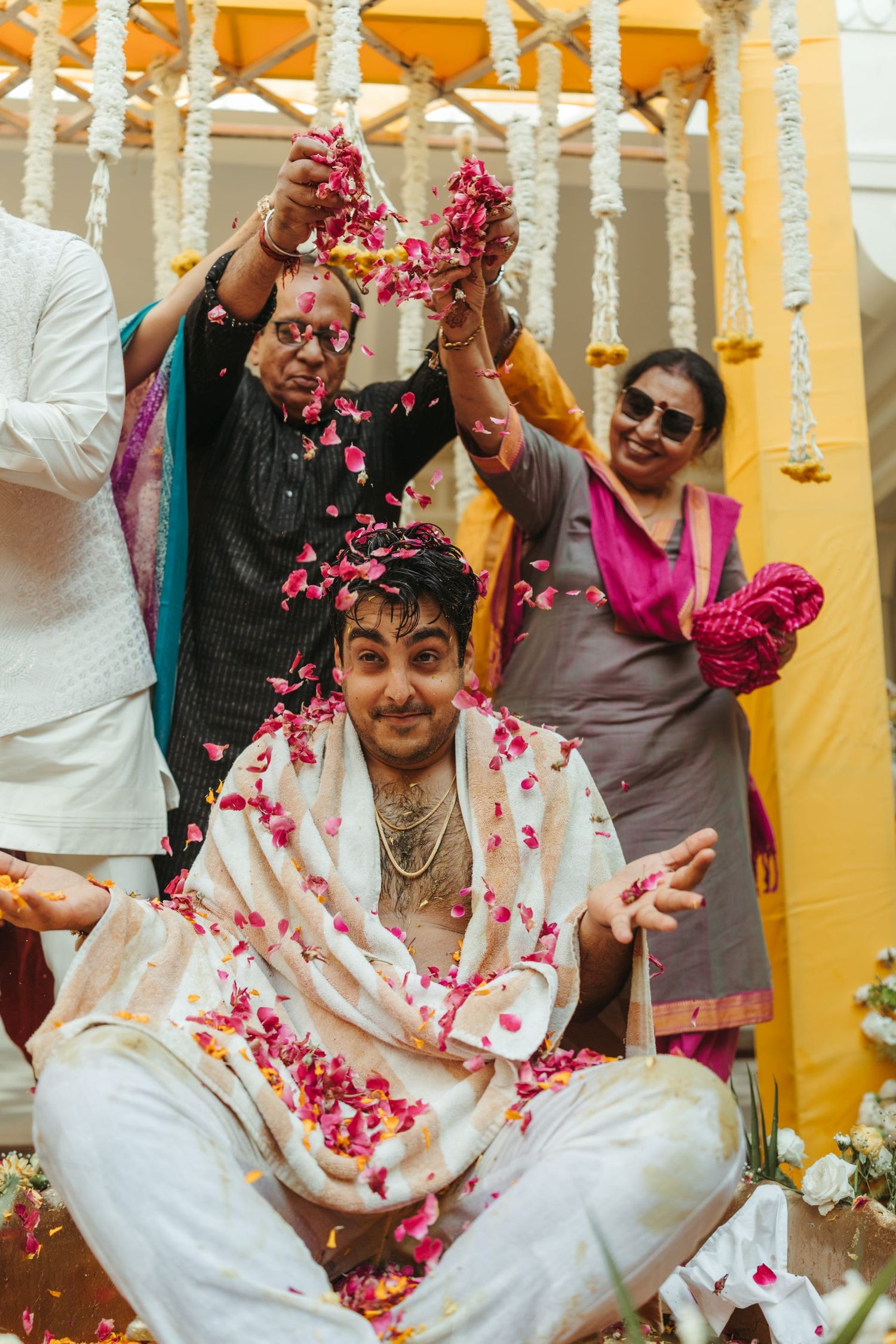 Celebratory moment with guests throwing pink flower petals during traditional ceremony.
