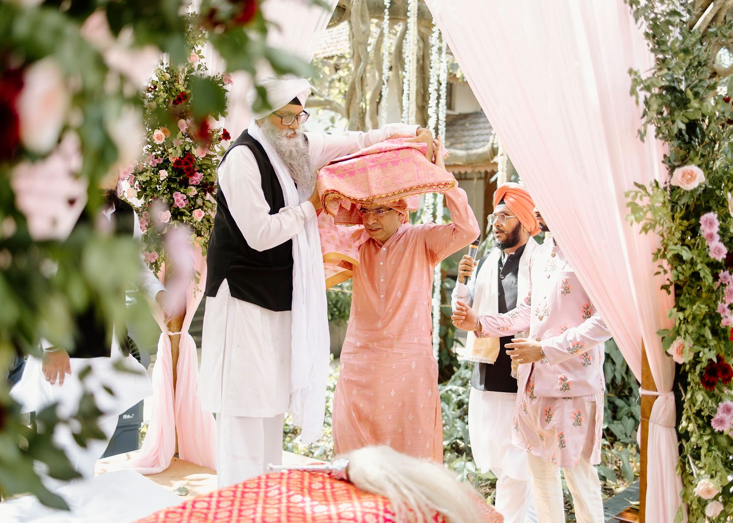 Pink and white draped wedding ceremony decor with floral arrangements creating a romantic atmosphere.