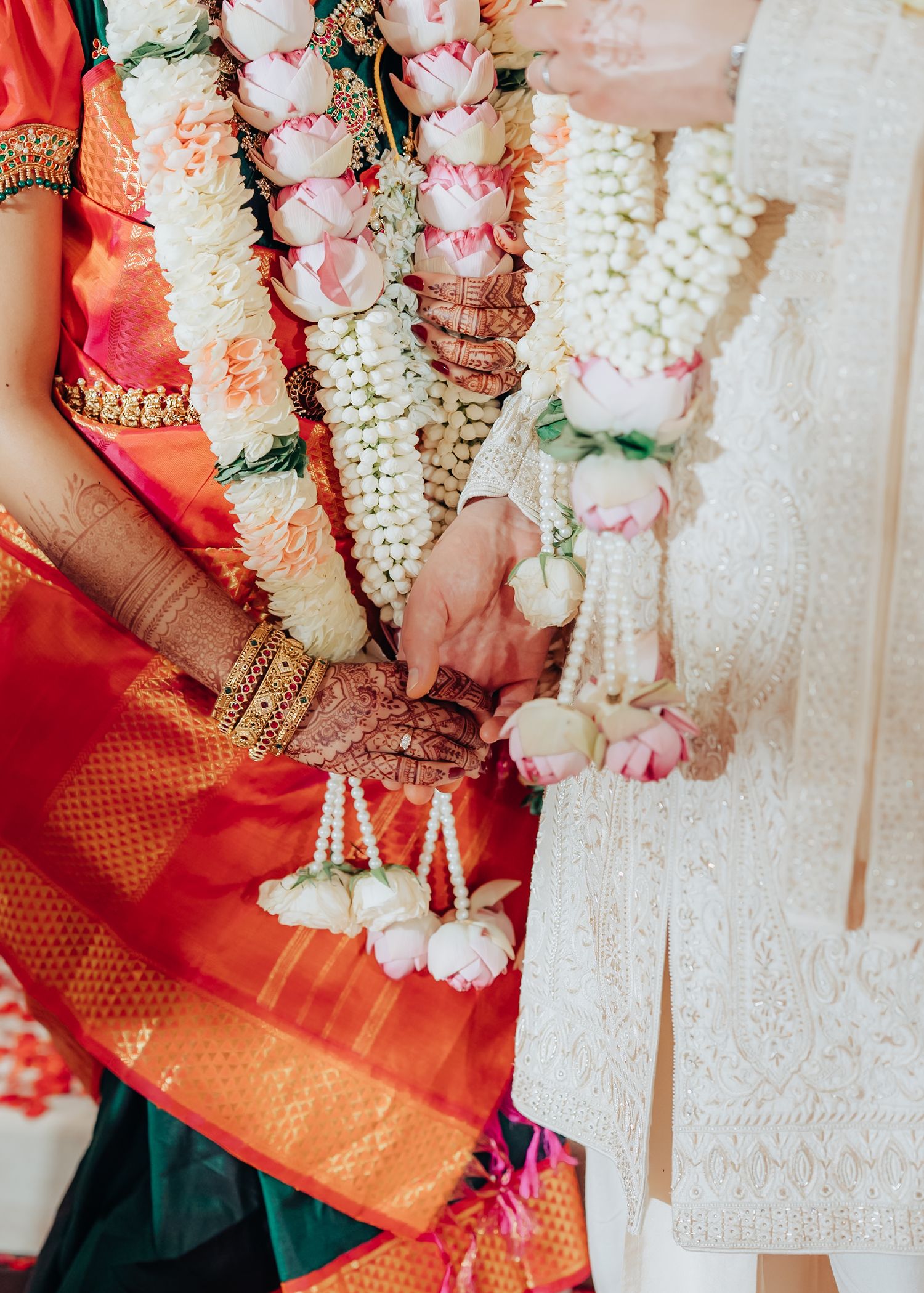 Close-up of traditional wedding garlands with white flowers and red silk details.