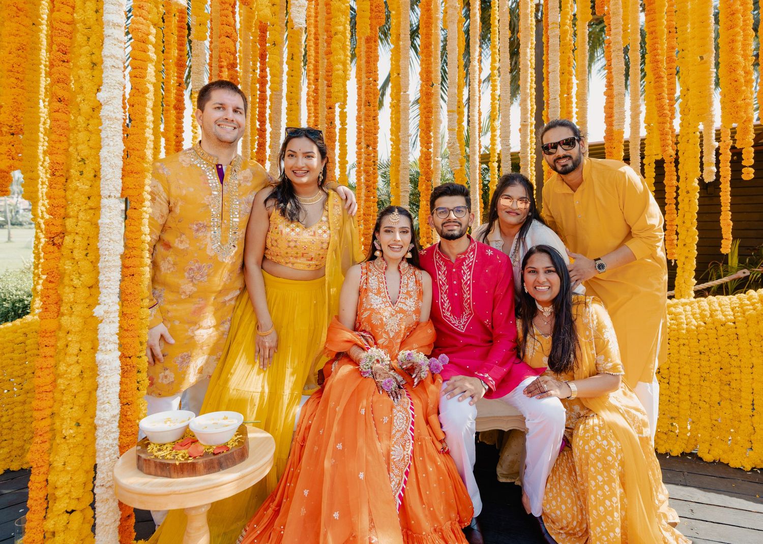 Traditional Indian wedding celebration with vibrant yellow marigold flower decorations hanging from above.