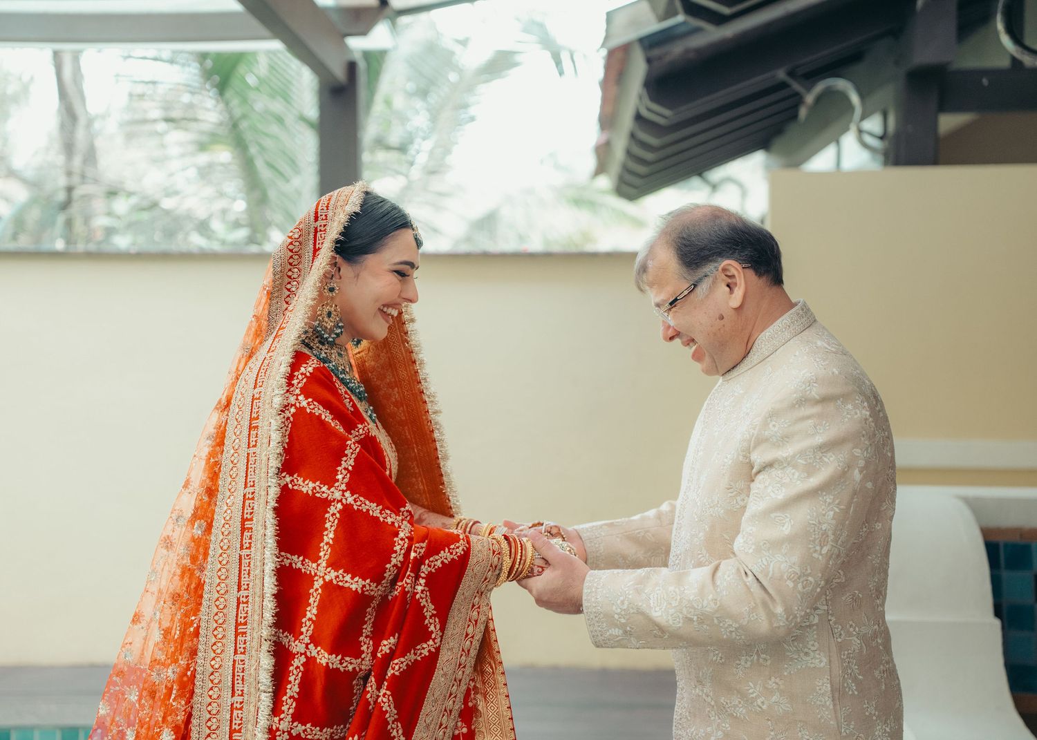 A couple shares an intimate moment during a traditional Indian wedding ceremony, with the bride in a bright red lehenga.