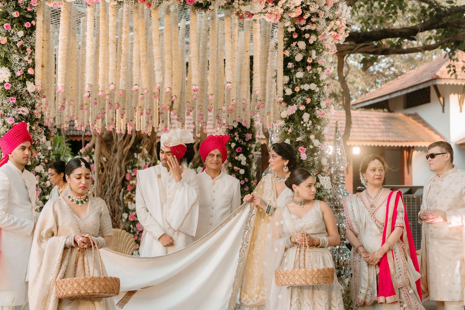 An elegant traditional Indian wedding ceremony with soft pink and beige decor under a dreamy canopy with floral elements.