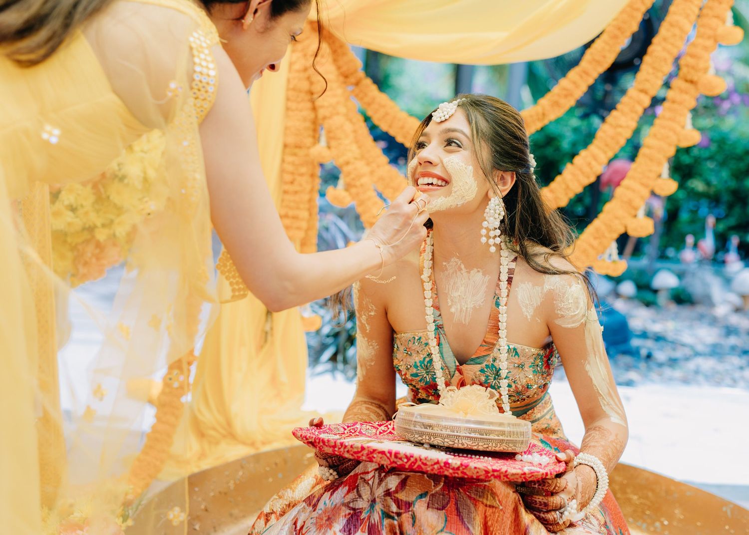 A joyful traditional Indian wedding ceremony with decorative gold and orange drapery in the background.