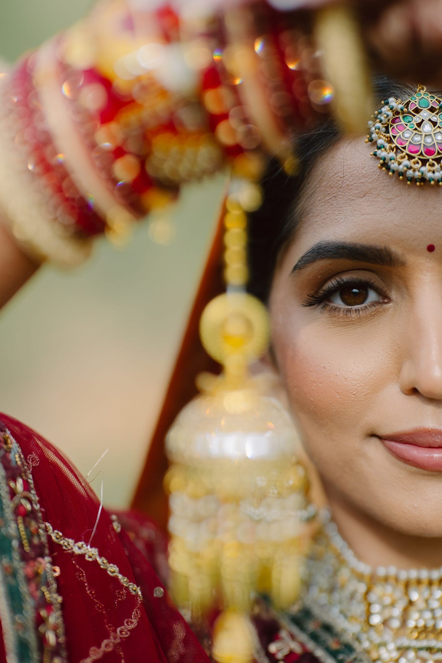Close-up detail of Indian bridal jewelry and traditional makeup with bindi.
