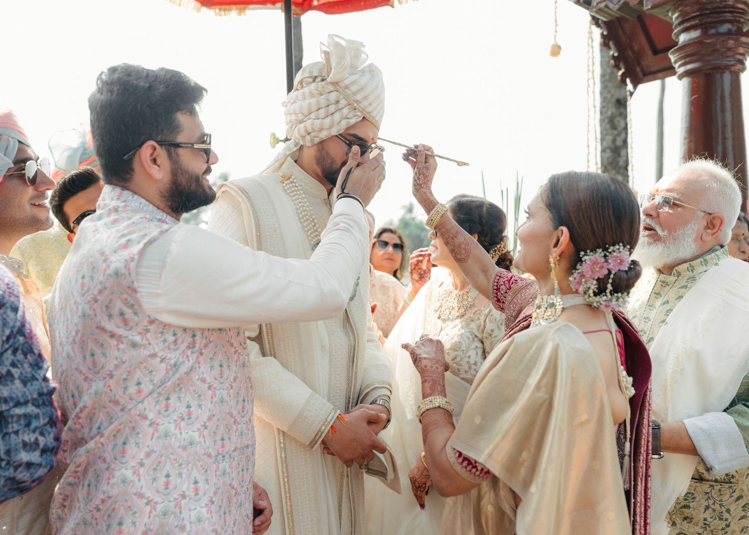 A traditional Indian wedding ceremony being conducted with guests dressed in elegant ivory and pastel attire.