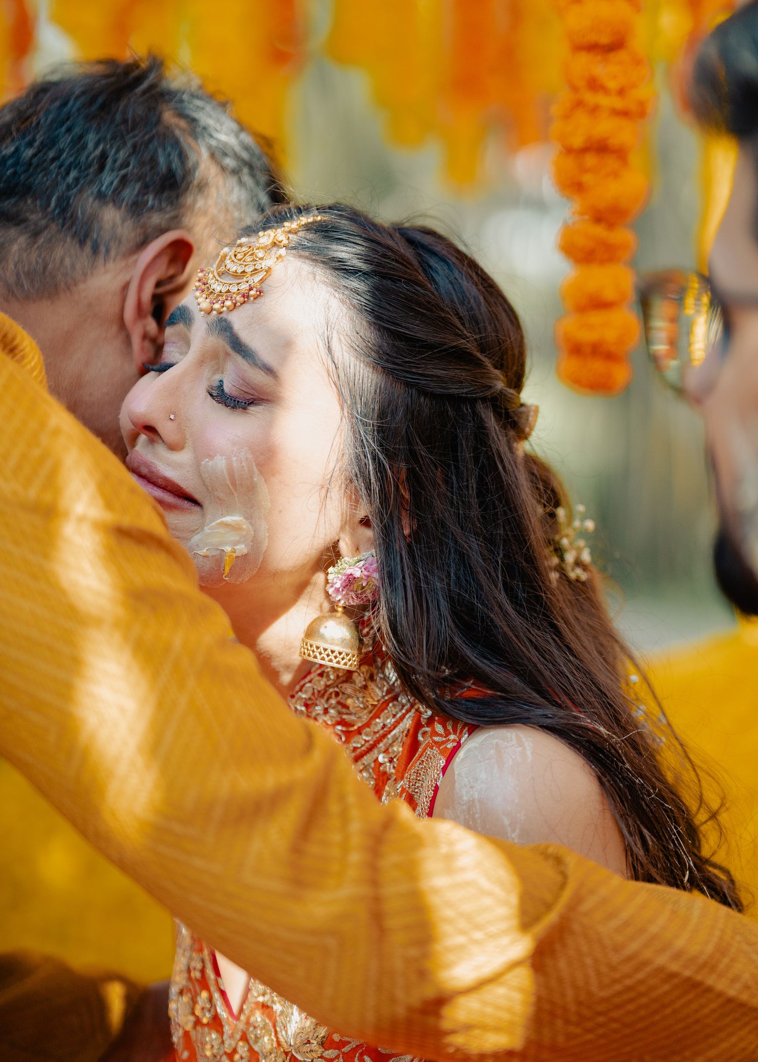 Close-up of wedding ceremony with traditional Indian jewelry and yellow fabric in foreground.