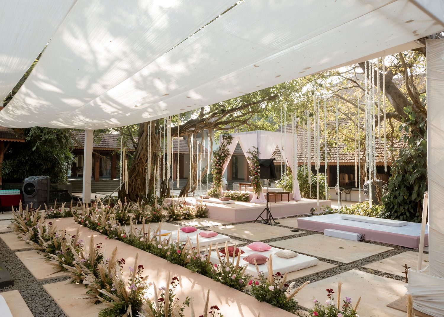 Panoramic view of an outdoor wedding venue decorated with white drapes and pink accents.