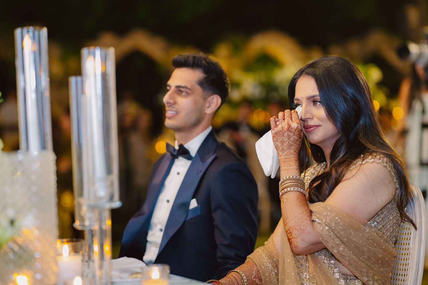 Couple pours champagne into a tower of glasses at an elegant celebration.