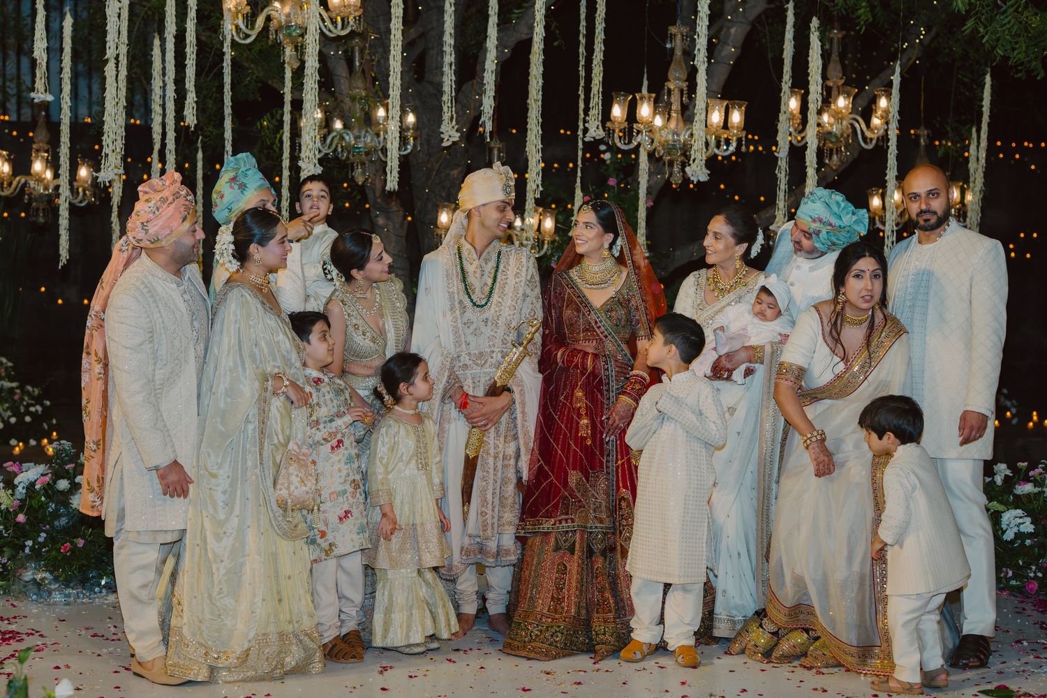 Large group photo of wedding guests in traditional Indian clothing at an evening celebration.