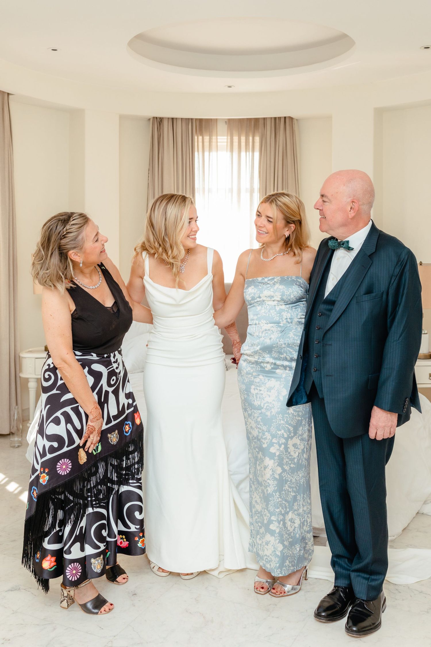 Wedding party in formal attire poses together in an elegant room with circular ceiling detail.