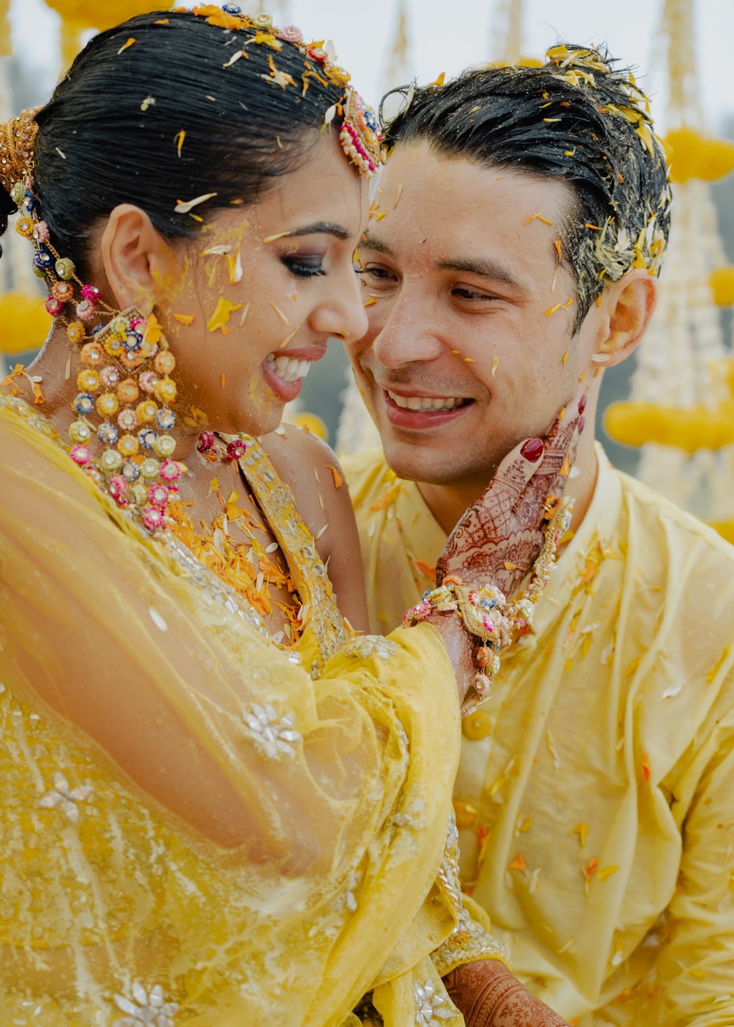 Couple shares joyful moments during their Haldi ceremony surrounded by yellow decorations and turmeric powder.