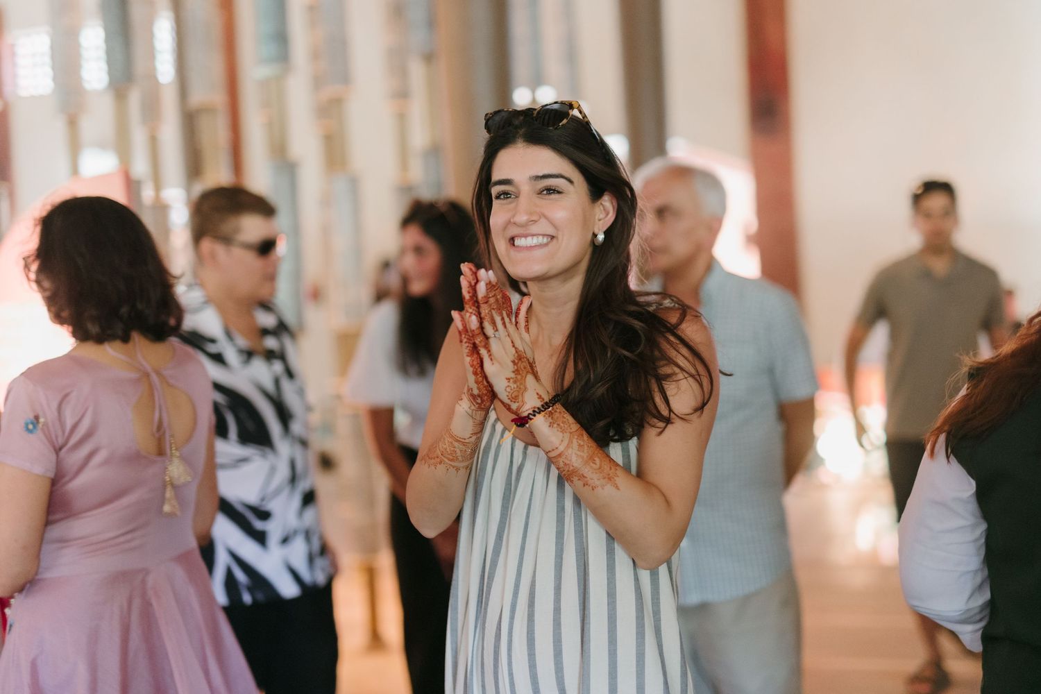 Diverse group mingles and dances with joyful expressions during an indoor celebration in a bright white room.