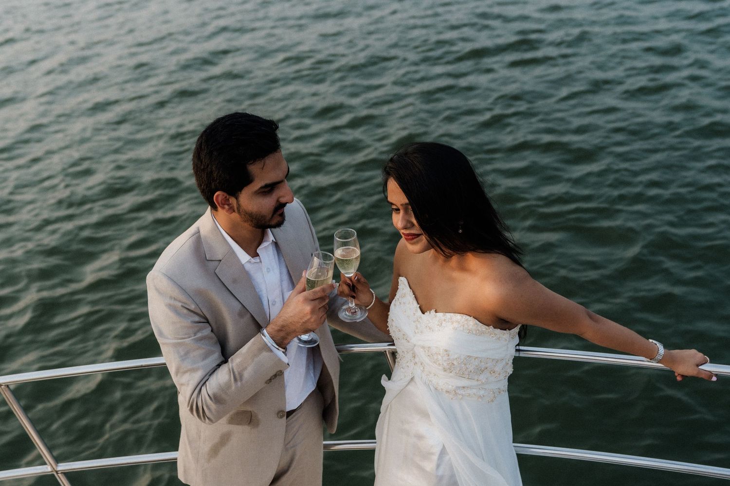 Two people enjoy an intimate moment on a boat with water in the background.