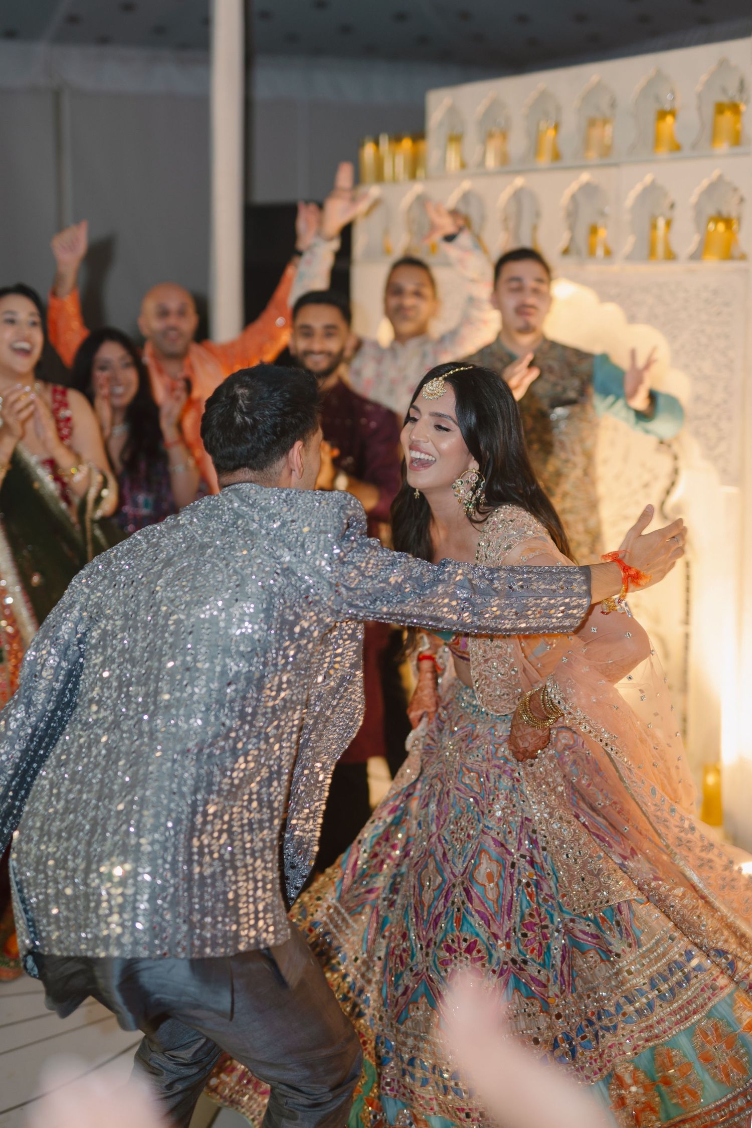 Guests dancing and celebrating at a festive Indian wedding reception with sparkly outfits.