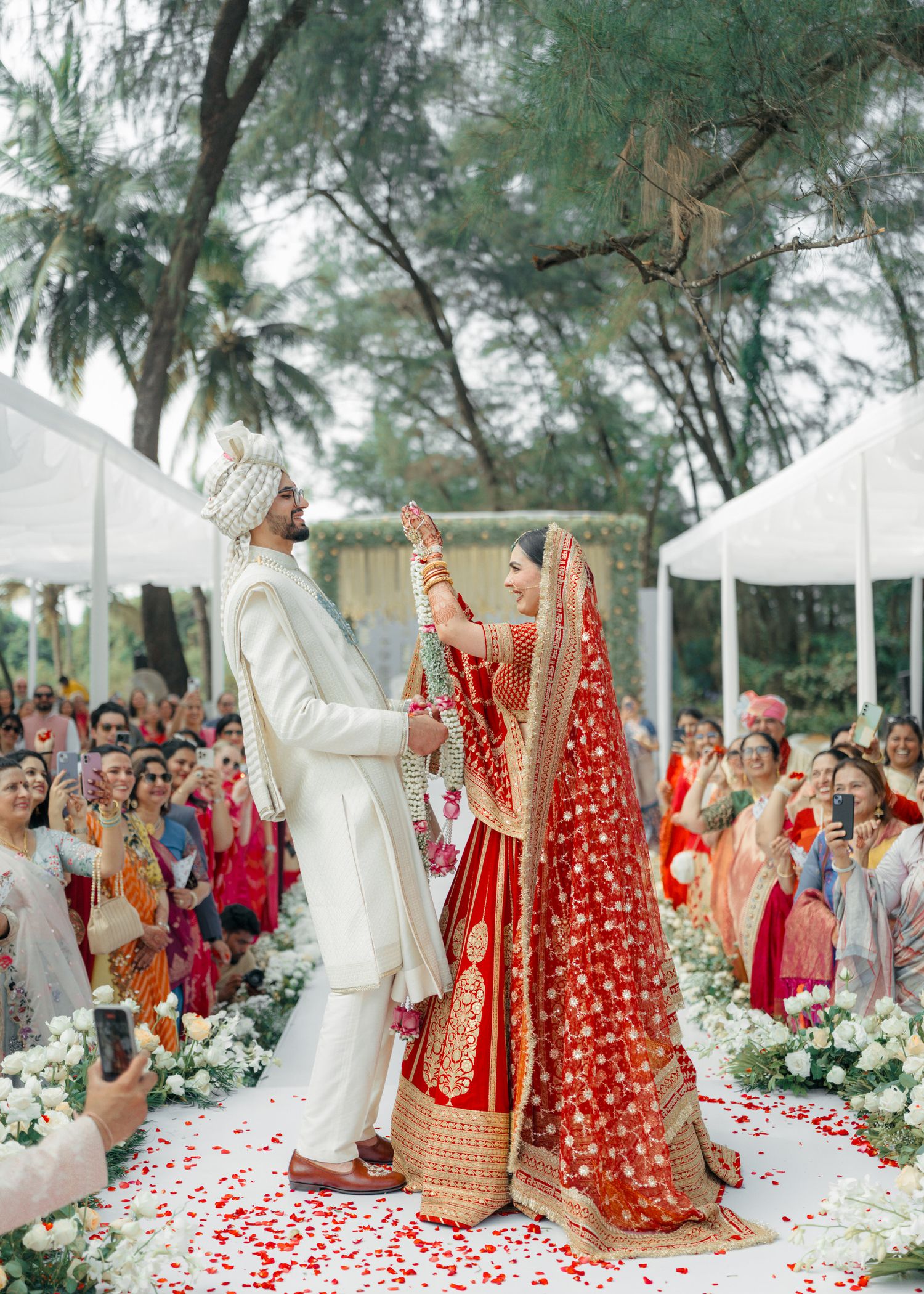 Traditional Indian wedding ceremony showing four sequential moments of vows and rituals on a beach with guests watching.