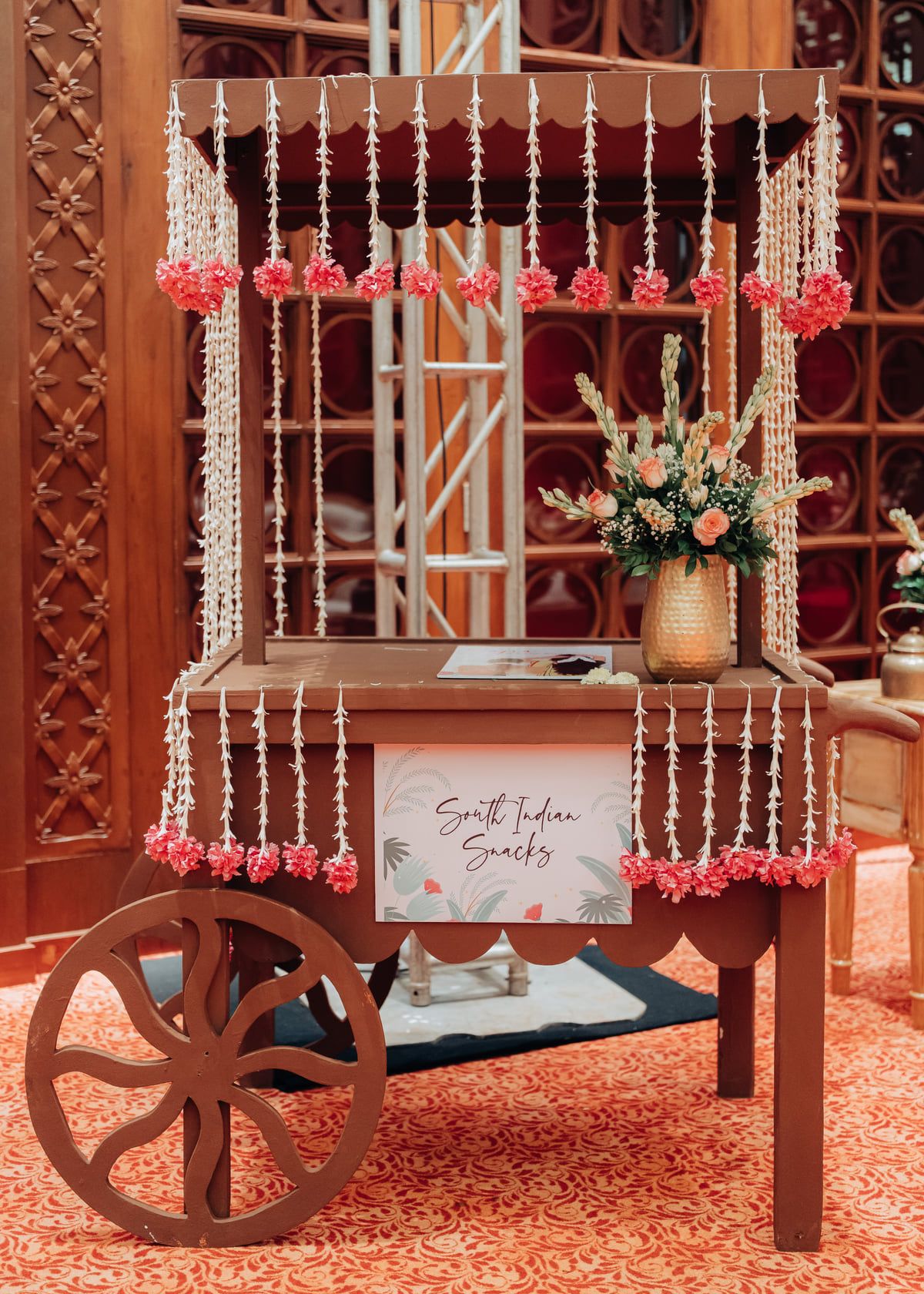 Vintage cart decorated with hanging floral strings and crystal beads displaying a wedding sign.