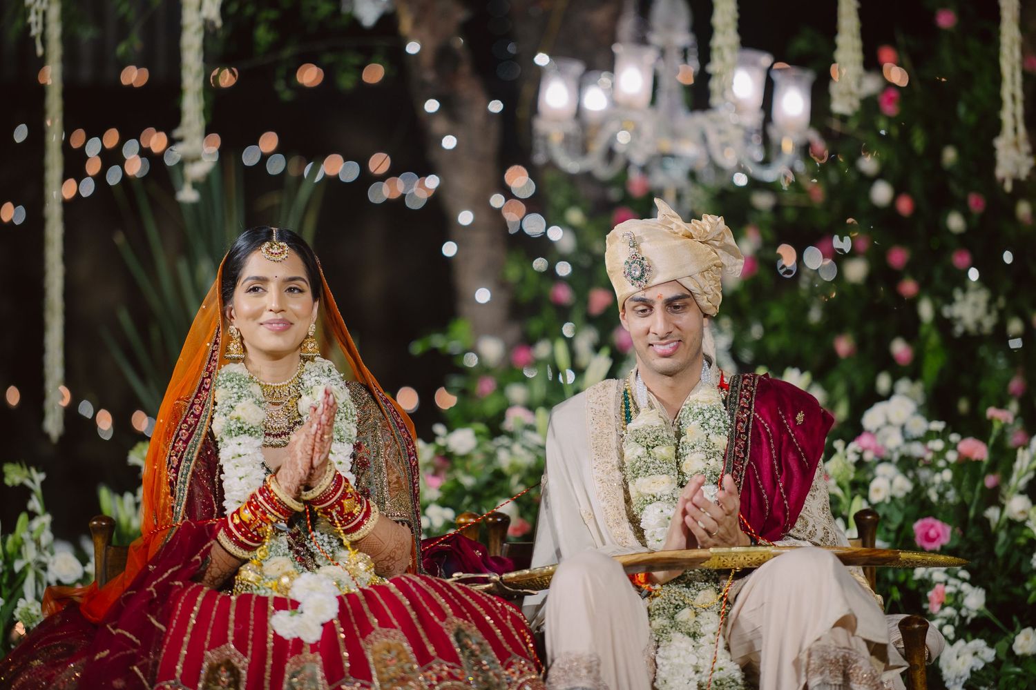 Elegant outdoor Indian wedding ceremony with floral decorations and string lights.