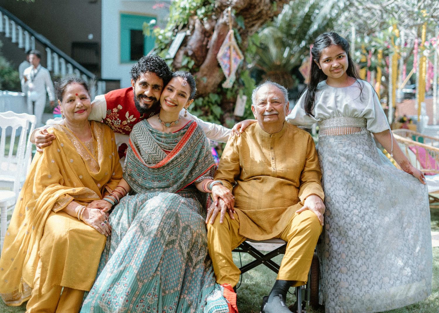 Family posing together in traditional Indian attire at a festive outdoor celebration, smiling warmly.