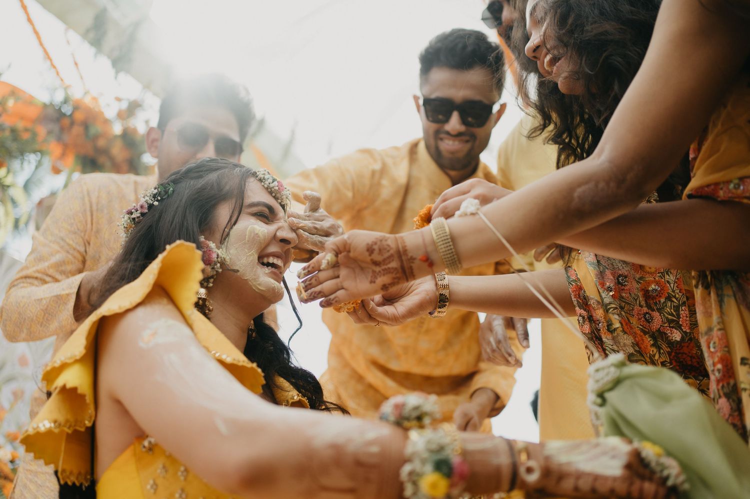 Traditional Indian Haldi ceremony celebration with guests applying turmeric paste during pre-wedding ritual.
