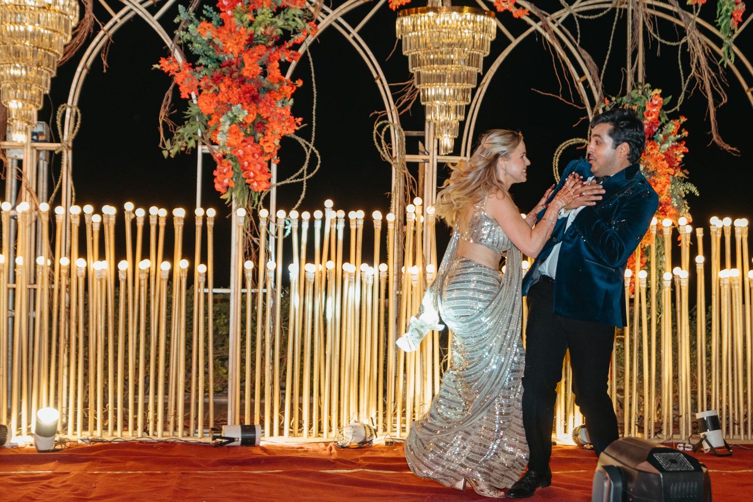 Wedding venue featuring elegant archways adorned with orange flowers and string lights.