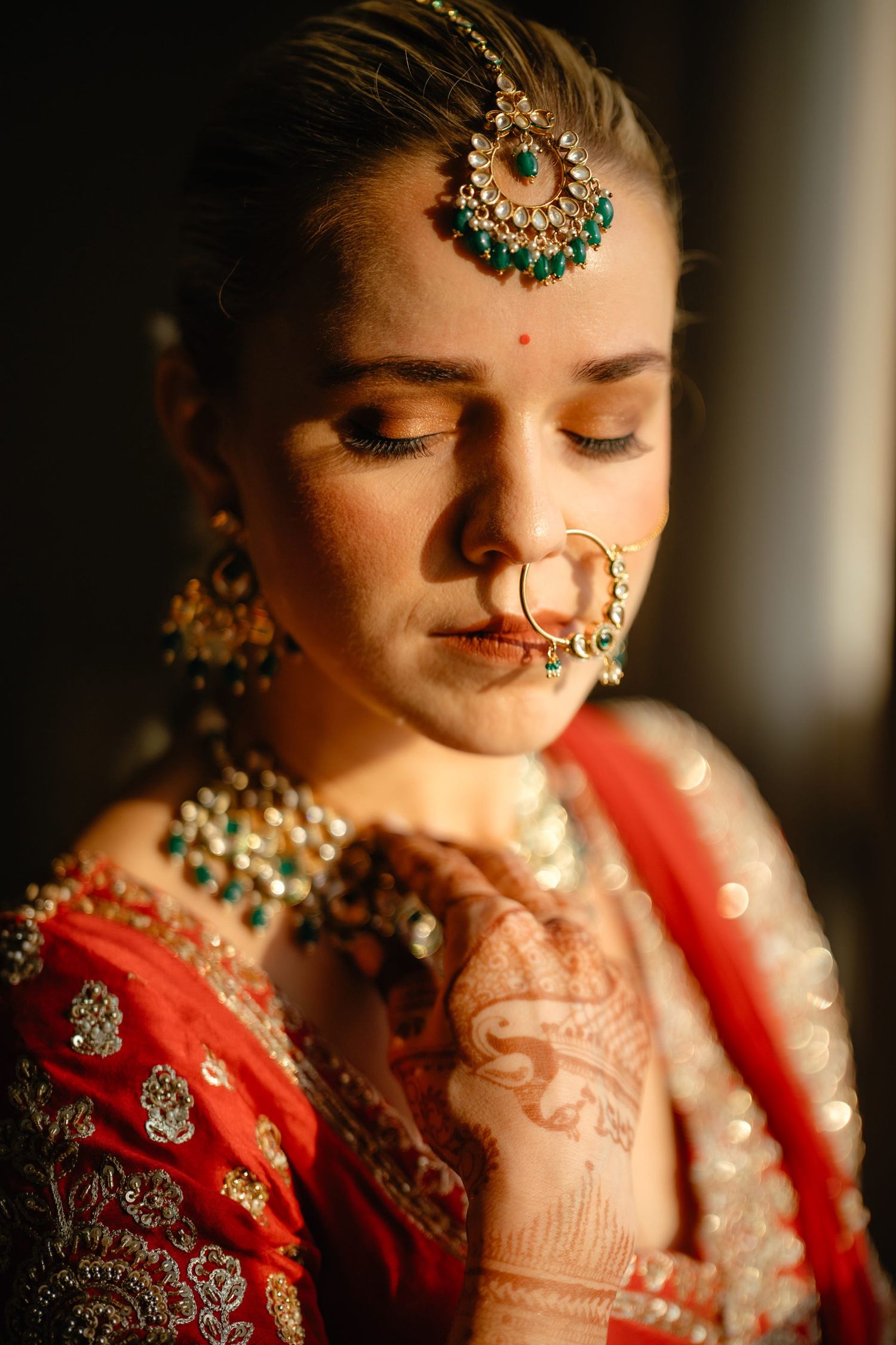 Close-up of Indian bridal jewelry and makeup in dramatic lighting.