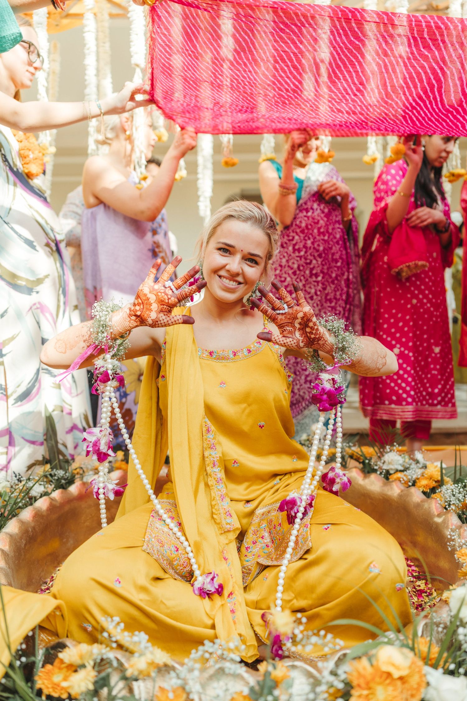 Festive celebration with guests in yellow and pink attire surrounded by flower petals.