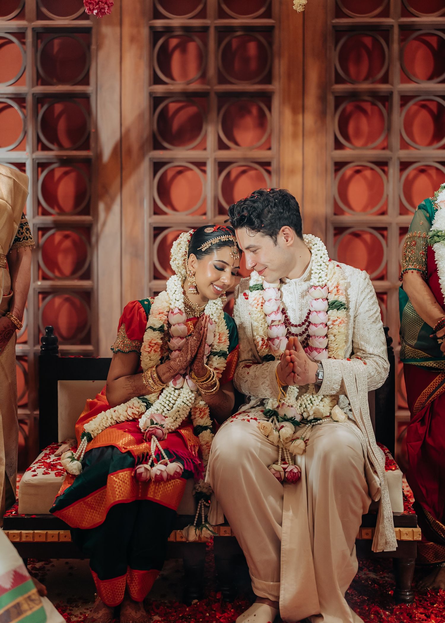 Traditional wedding ceremony with decorative red backdrop and hanging floral arrangements.