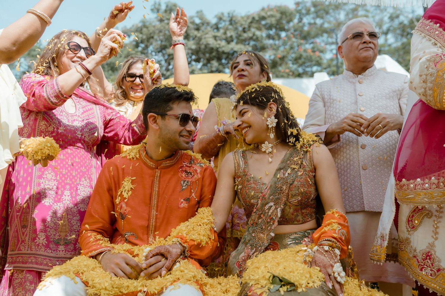 Traditional Indian wedding celebration with guests wearing vibrant orange and pink attire during a festive ceremony.