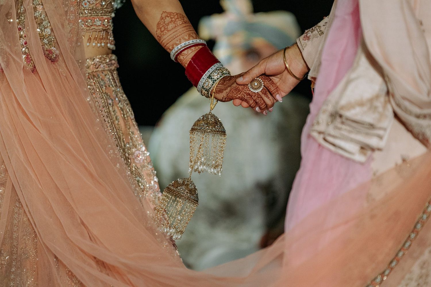 Close-up of intricate henna designs on hands with bangles and jewelry in traditional Indian wedding style.