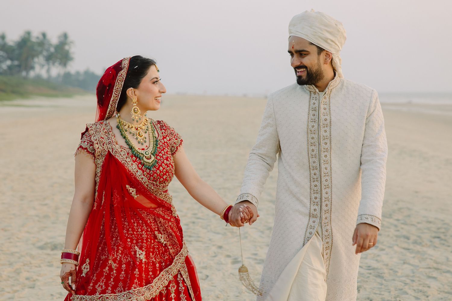 Romantic beach photoshoot featuring traditional wedding attire against sandy backdrop.