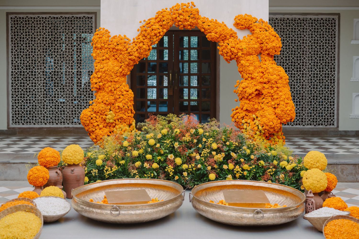 Vibrant orange marigold garlands decorate an elegant white archway.