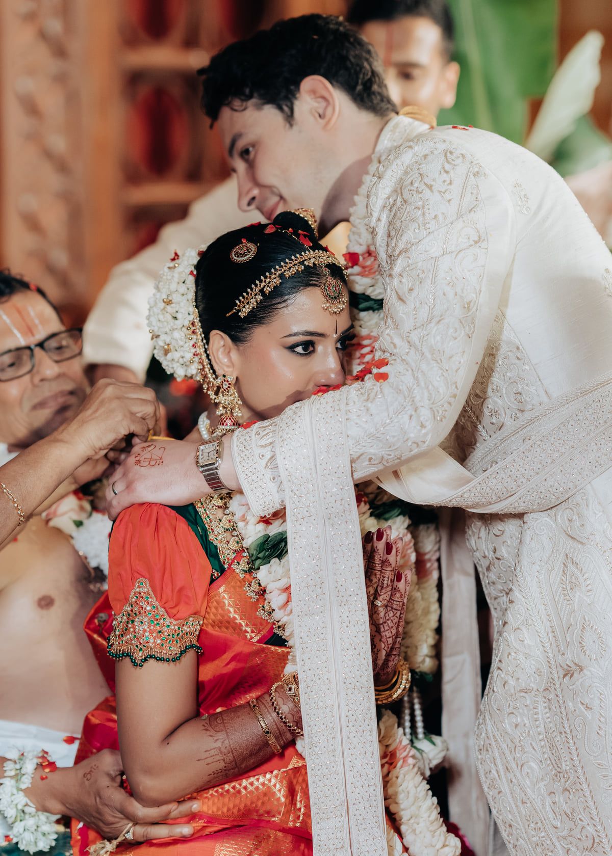 Intimate moment during a traditional wedding ceremony with elaborate cultural decorations.