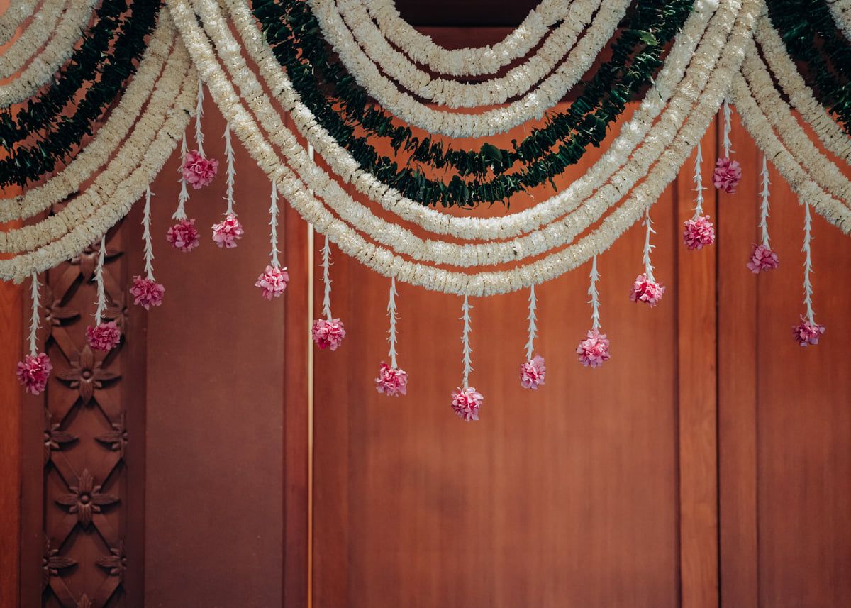 Decorative floral garlands and hanging ornaments arranged in scalloped patterns against a wooden wall.