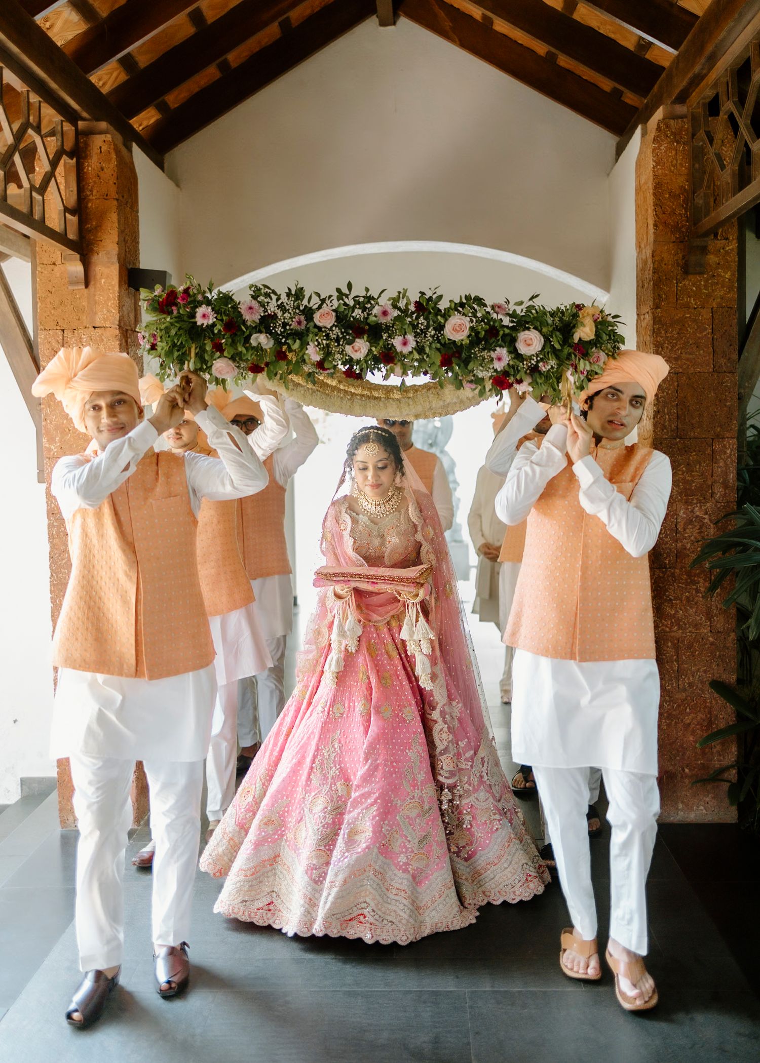 Wedding ceremony participants in white and pink attire performing traditional customs.