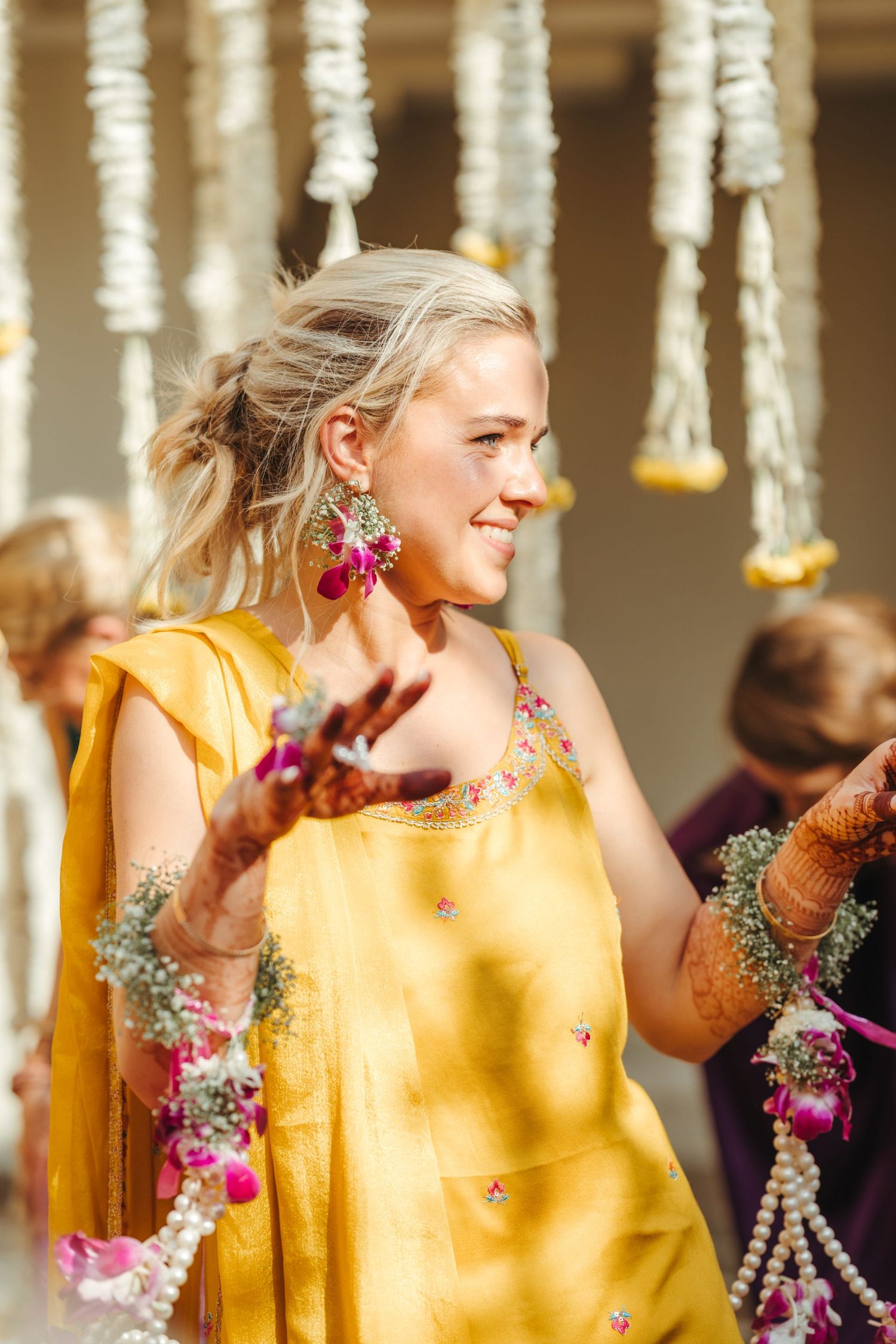 Guests in bright yellow outfits celebrate during a festive cultural ceremony with floral decorations.