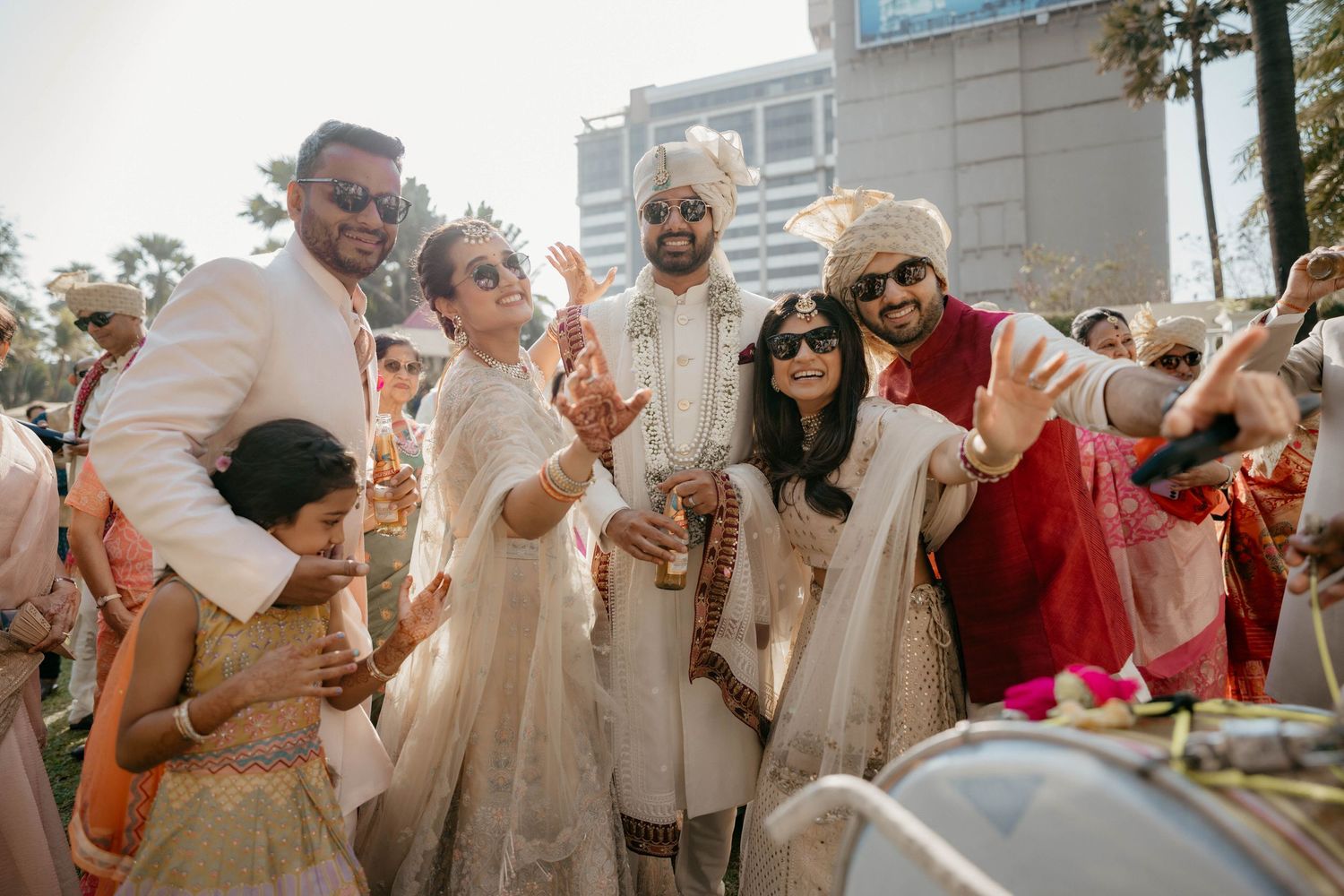 A joyous celebration at an outdoor wedding with people dancing and smiling in traditional Indian attire.