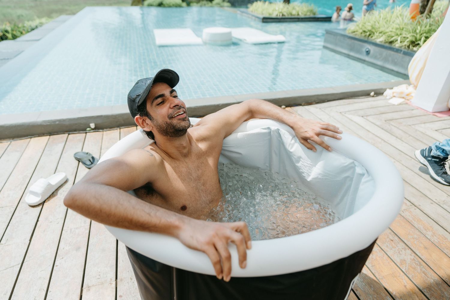 Four sequential photos show someone relaxing in a freestanding white bathtub on an outdoor wooden deck.