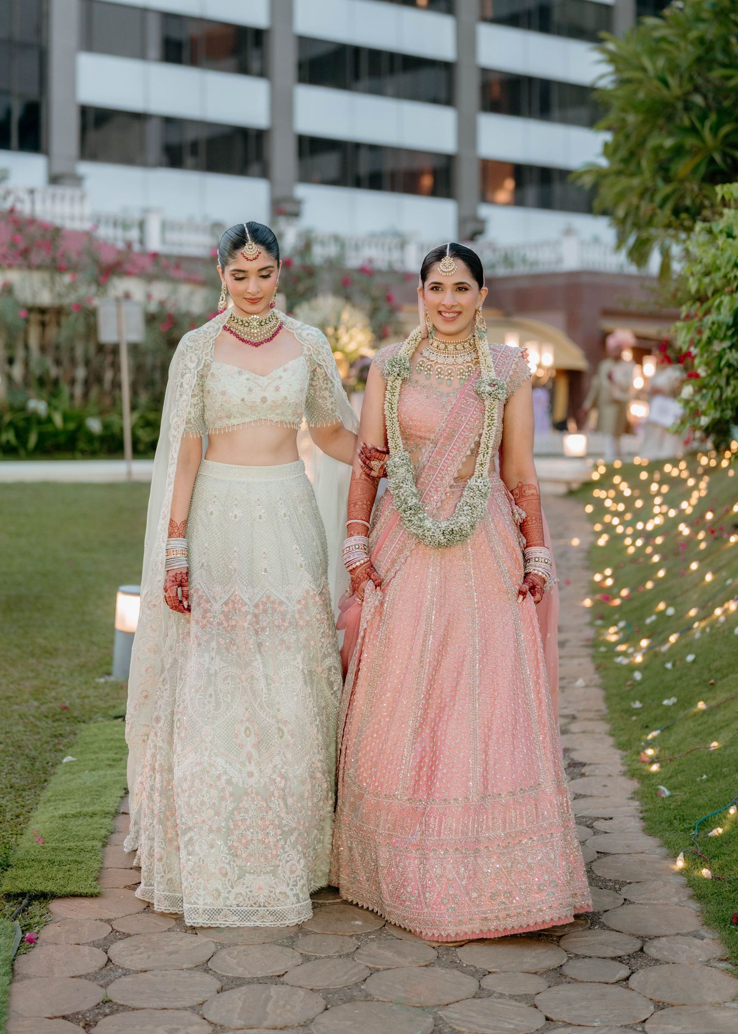 Nastasia and her bridal companion wearing traditional South Asian lehengas during an evening wedding moment at Taj Lands End Mumbai, capture