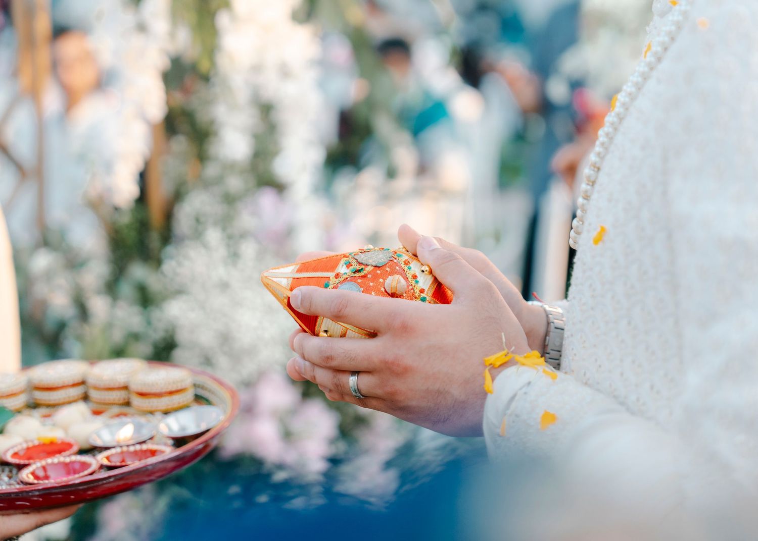 Hands holding a traditional Russian tea cup with ornate designs during an outdoor gathering with bokeh background.