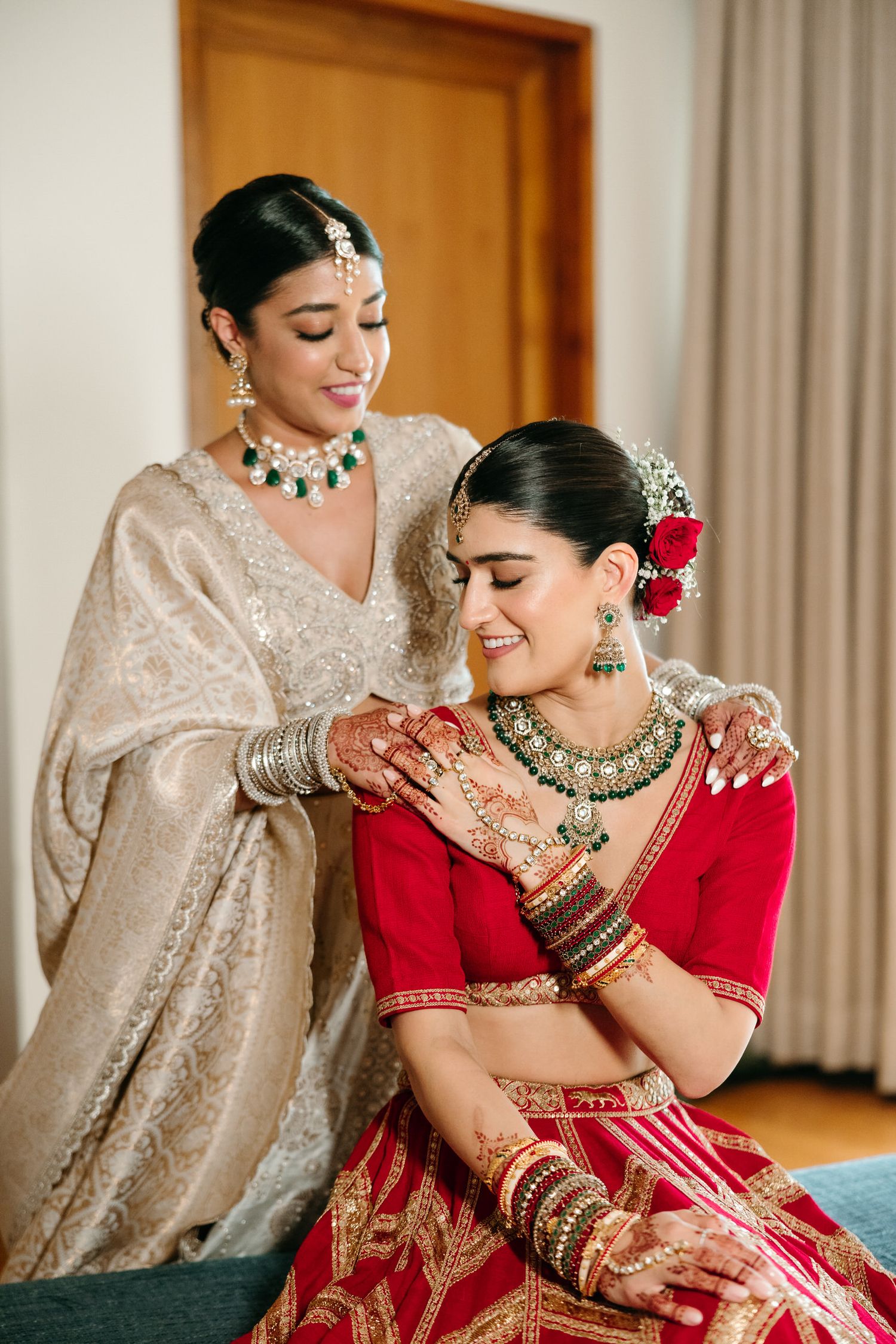 Traditional South Asian wedding attire featuring ornate jewelry and henna designs in red and beige colors.