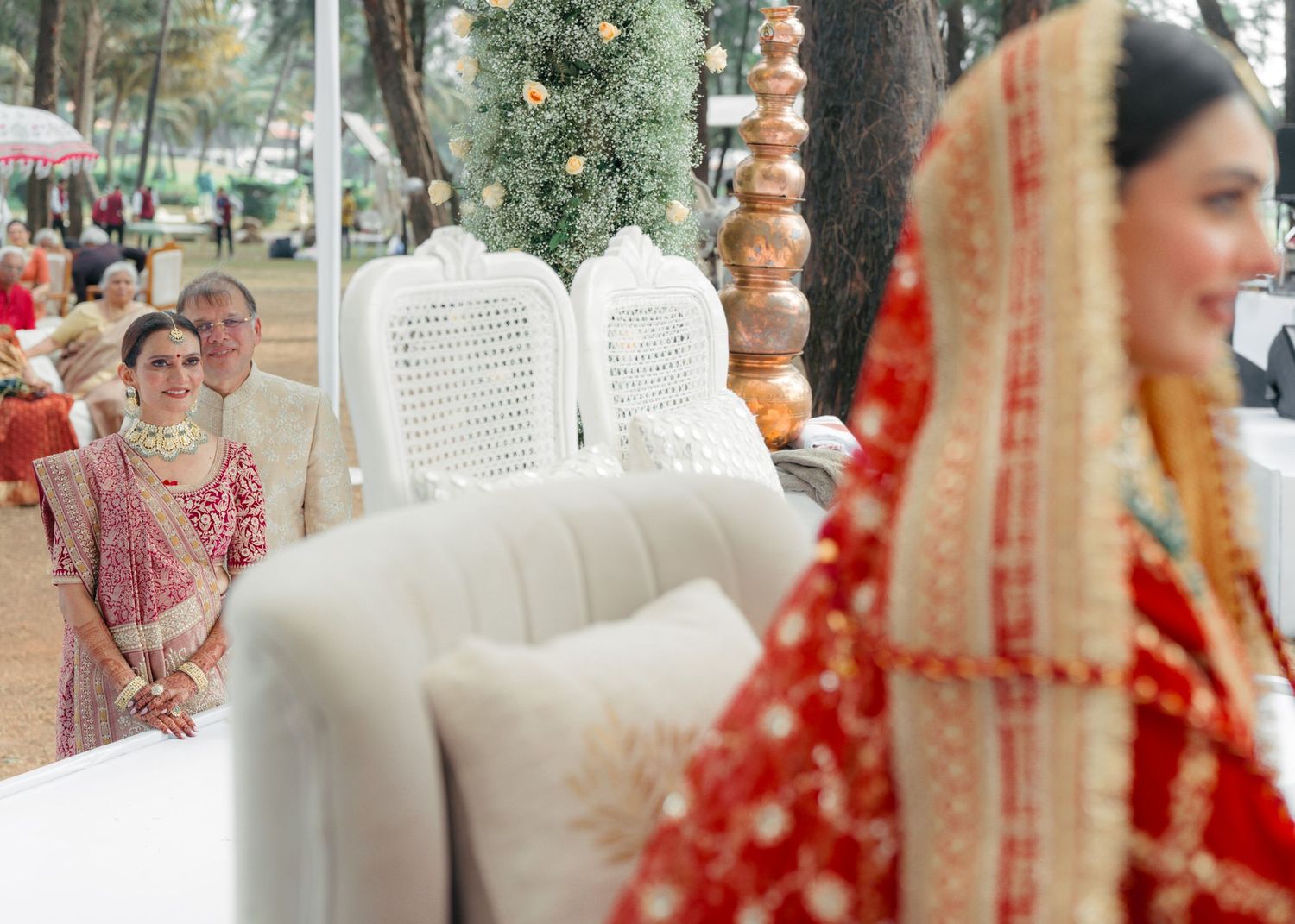 A traditional Indian wedding scene with elegant white chairs and decorative elements featuring bright red bridal attire.