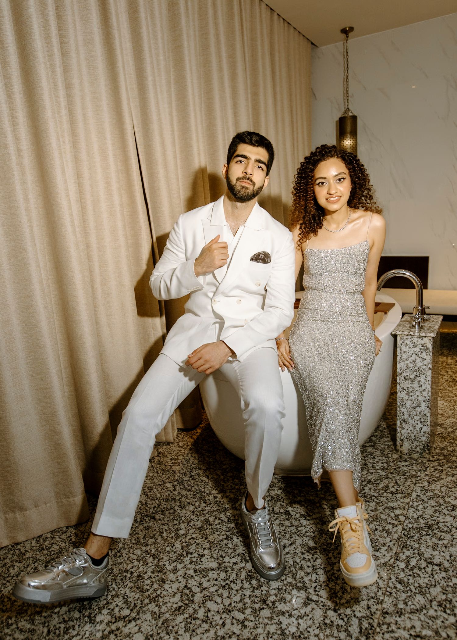 Couple poses for casual photos on textured carpet in wedding attire.