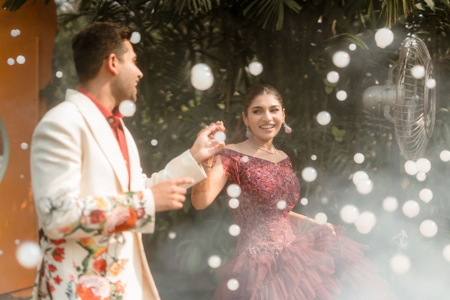 Wedding celebration scene with string lights creating bokeh effects in an outdoor evening setting.
