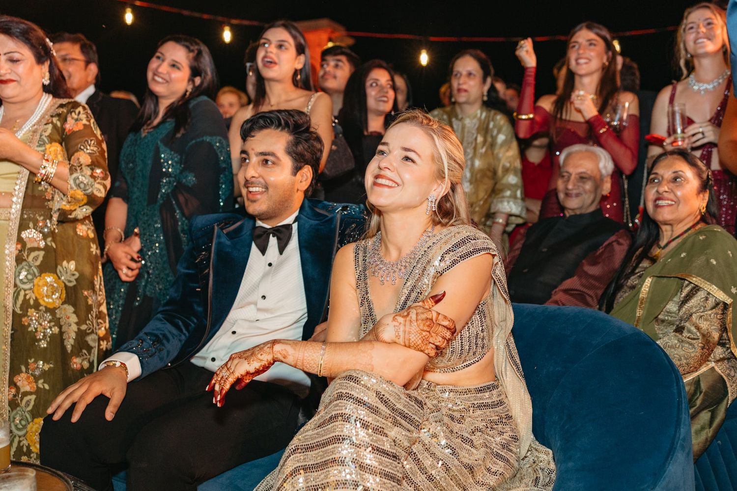 Wedding guests enjoying a lively celebration with elegant decor and orange floral arrangements.