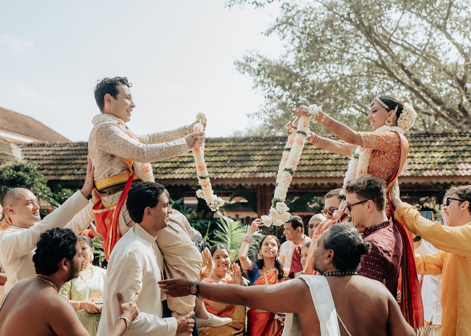 Celebratory outdoor wedding scene with guests in traditional attire.