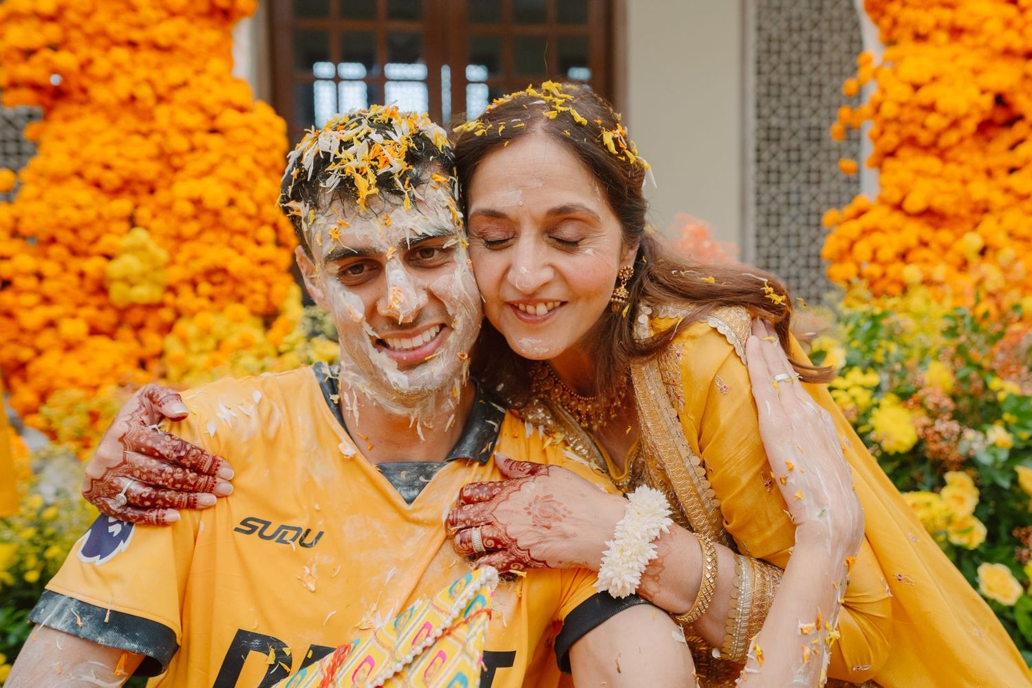 Yellow turmeric powder covers joyful participants during traditional Indian pre-wedding celebrations.