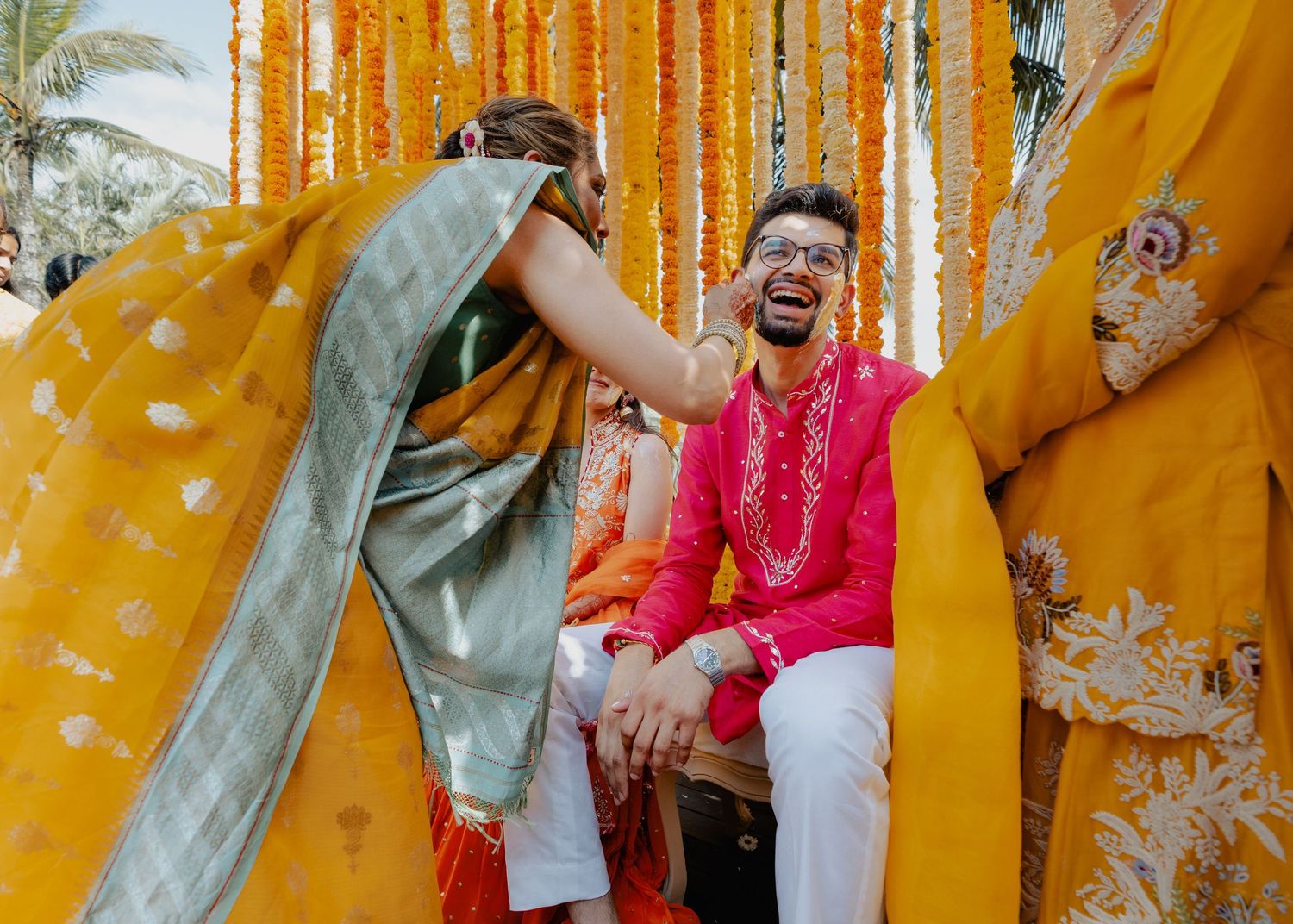 A celebratory moment at an Indian wedding ceremony with bright yellow and orange marigold decorations.
