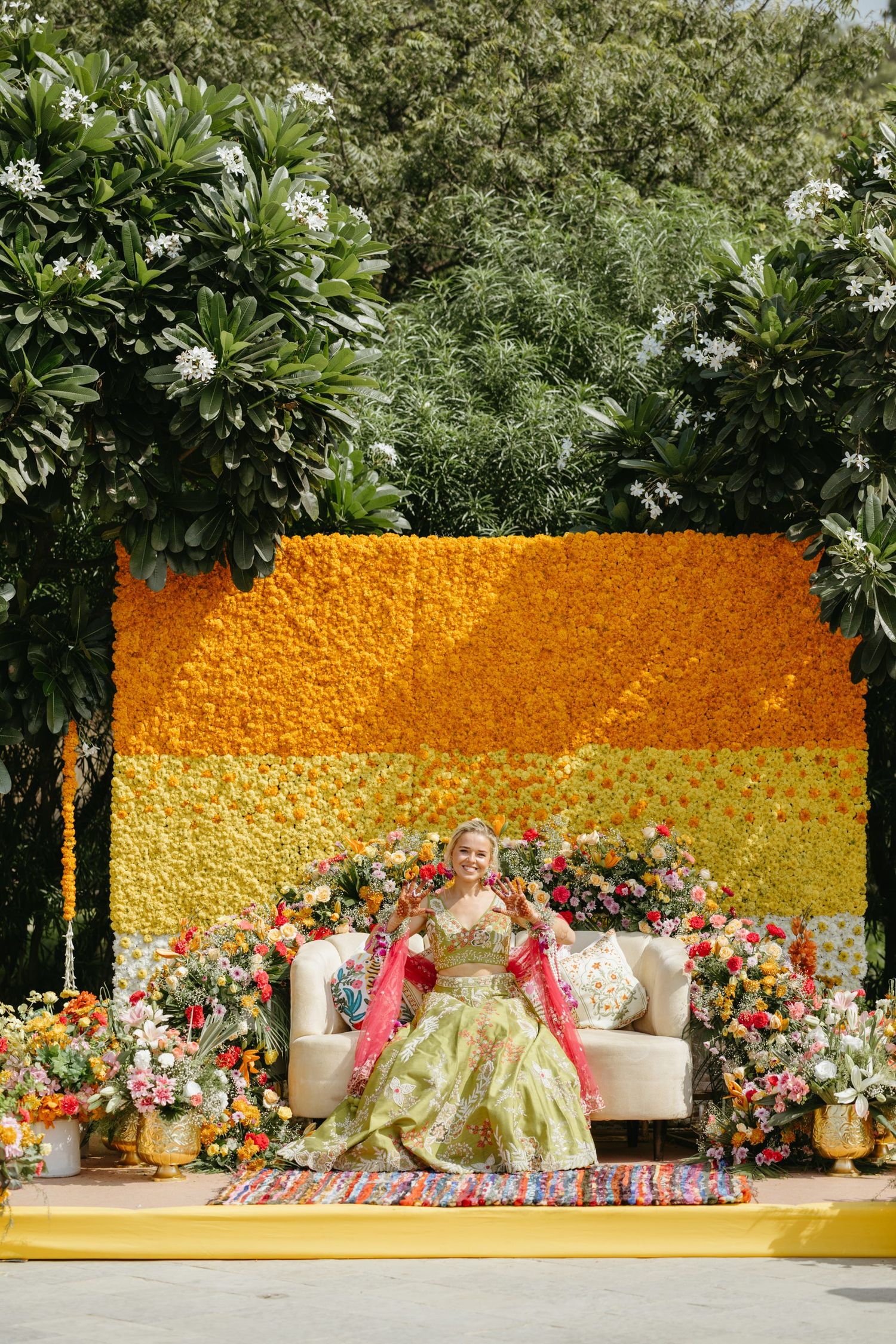 Elegant wedding stage setup with orange marigold wall backdrop and floral arrangements.