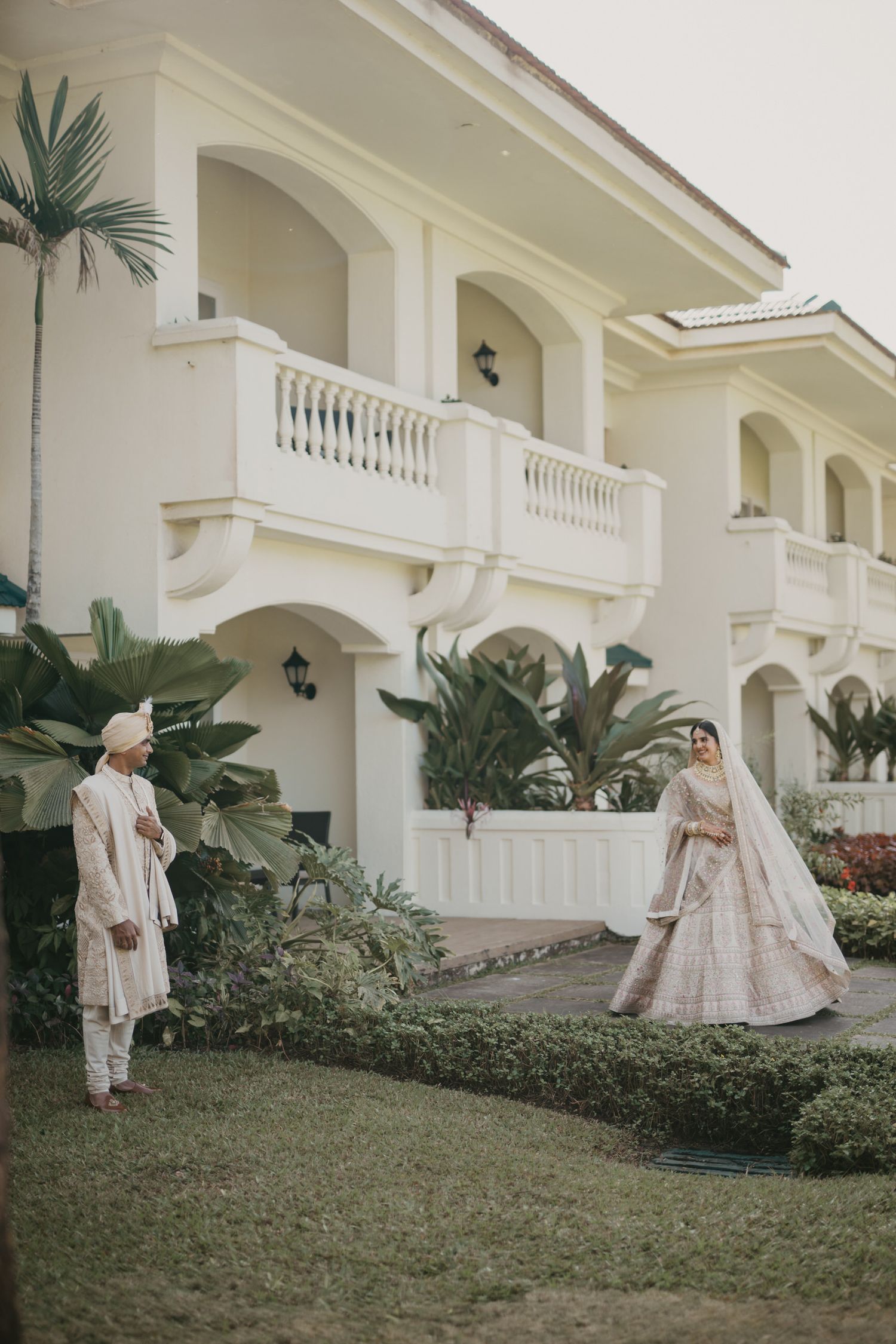 Elegant wedding photo session at white colonial-style building with manicured gardens.